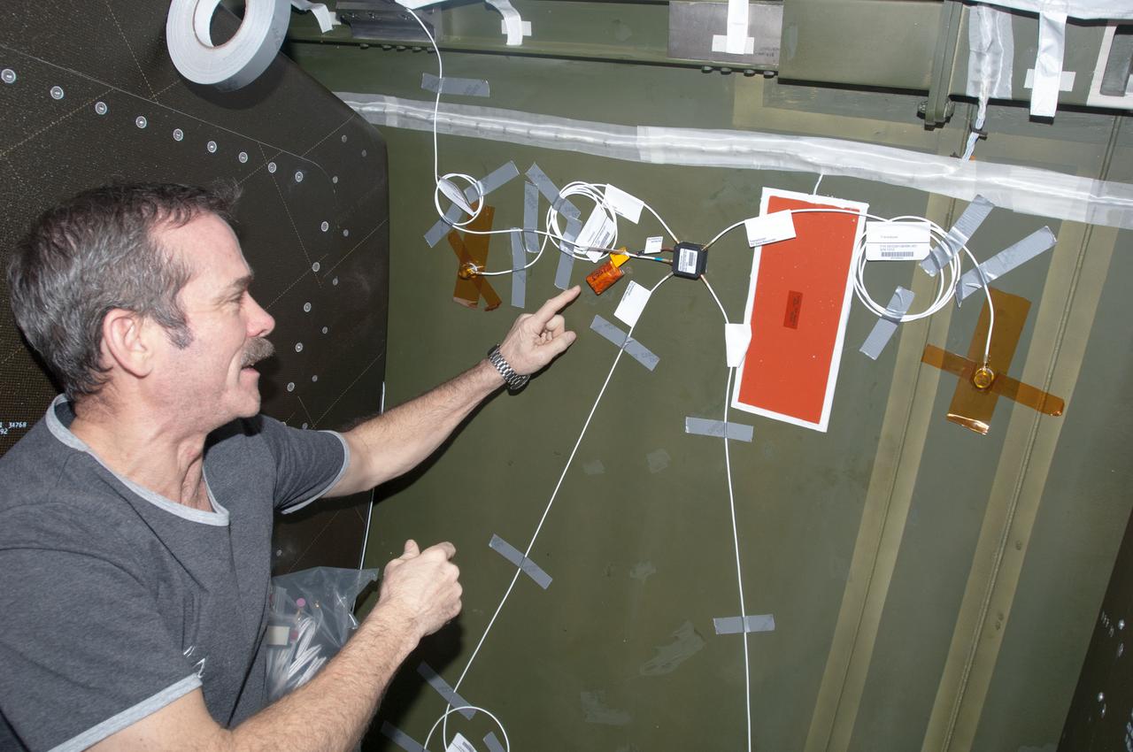 ISS034-E-038211 (1 Feb. 2013) --- Canadian Space Agency astronaut Chris Hadfield, Expedition 34 flight engineer, installs Ultra-Sonic Background Noise Tests (UBNT) sensors behind a rack in the Destiny laboratory, using the International Space Station (ISS) as Testbed for Analog Research (ISTAR) procedures. These sensors detect high frequency noise levels generated by ISS hardware and equipment operating within Destiny.