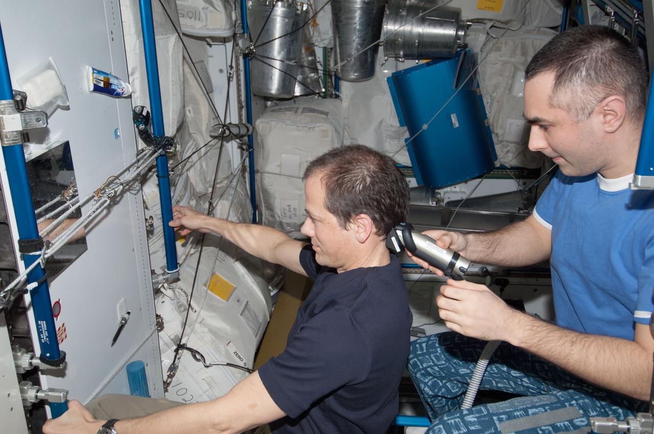 ISS034-E-054688 (24 Feb. 2013) --- NASA astronaut Tom Marshburn (at left), Expedition 34 flight engineer, looks into a mirror as Russian cosmonaut Evgeny Tarelkin, flight engineer, gives him a hair trim in the Tranquility node aboard the International Space Station.
