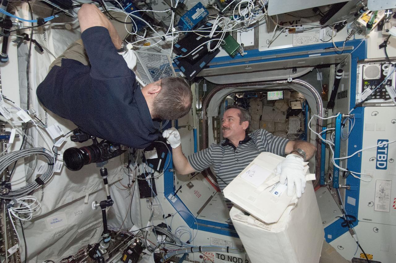ISS034-E-067263 (12 March 2013) --- Canadian astronaut Chris Hadfield, right, assists fellow Expedition 34 flight engineer and NASA astronaut Tom Marshburn during Minus Eighty-Degree Laboratory Freezer for International Space Station (MELFI)operations. The two are doing transfers of samples connected to the General Laboratory Active Cryogenic ISS Experiment Refrigerator or GLACIER in the U.S. lab Destiny.