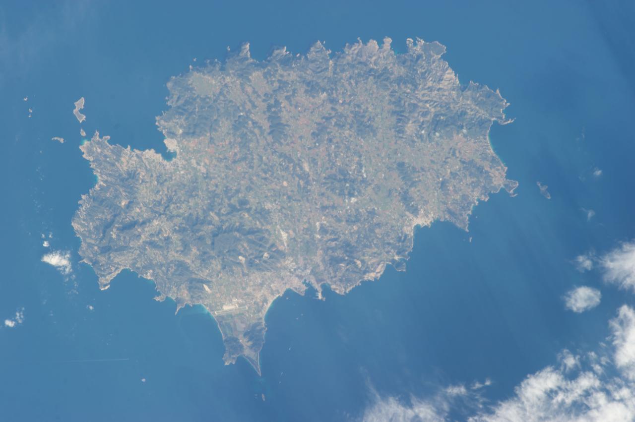 ISS035-E-007431 (22 March 2013) ---  One of the Expedition 35 crew members aboard the Earth-orbiting International Space Station used a digital camera equipped with a 400 millimeter lens to capture this image of the island of Ibiza (Eivissa in the native Catalan language), located off of the southeastern coast of Spain.  Ibiza is part of the Balearic archipelago. Together with the neighboring island of Formentera (not shown), it comprises the Pine Islands of the western archipelago. The largest cities on the island, Ibiza Town, Sant Antoni de Portmany, and Santa Eularia des Riu, appear as white to pink regions near coastal bays in the image.  Much of the lowland interior of the island is covered with green to light brown agricultural fields; some are still in active production for such crops as wheat, olives, and grapes but many fields are inactive and experiencing regrowth of native trees such as pine (Pinus halpensis) and savine (Juniperus phoenicea). The northern and southwestern coastlines are hilly (grey-brown regions), with the highest peak (Sa Talaia, 475 meters above sea level) located in the southwestern region. Like many of the Balearic Islands, the major industry of Ibiza is European tourism, and it is particularly well known for the nightlife of Ibiza Town and Sant Antoni de Portmany. Ships near Ibiza Town and a ship wake off the southwestern coastline are visible at image lower left. The island hosts a large variety of birds and lizards; however no large land fauna are present. The Mediterranean Sea to the southeast of the island appears dark in the image due to shadowing by clouds, just visible at the lower right corner of the image.