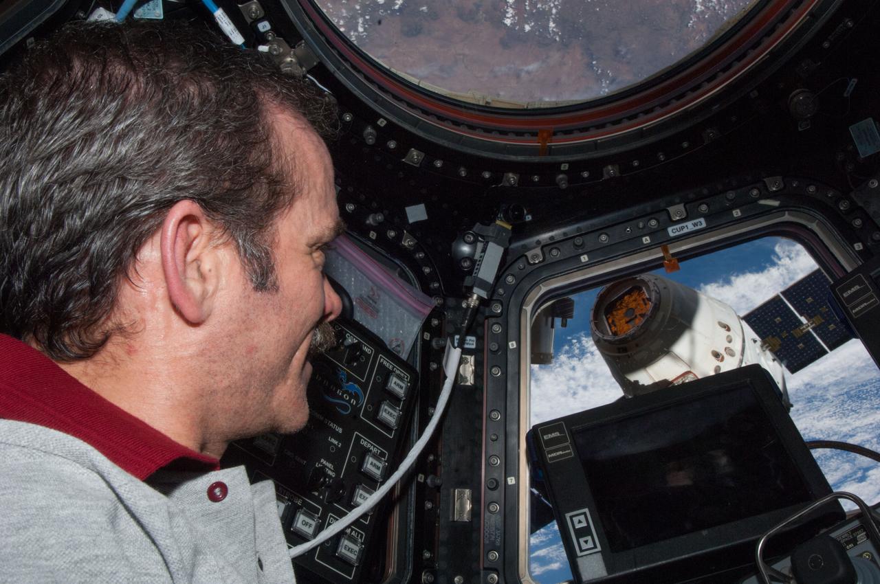 ISS035-E-010134 (26 March 2013) --- Expedition 35 Commander Chris Hadfield of the Canadian Space Agency is pictured in the Cupola on the International Space Station during the operations that ultimately led to the release of the SpaceX Dragon-2 spacecraft for its return to Earth after a three-week stay aboard the orbital outpost. The Dragon was scheduled to make a landing in the Pacific Ocean, off the coast of California, later in the day.