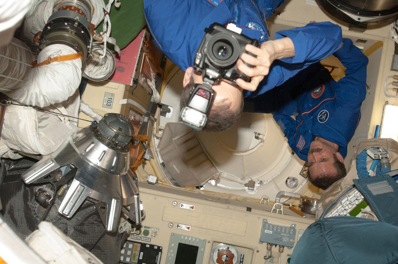 ISS035-E-010577 (29 March 2013) --- When there is a reunion taking place, one can almost always anticipate there will be multiple cameras present. There is no exception to that rule in this scene aboard the International Space Station in the Poisk or Mini-Research Module 2 (MRM2), as the two crew components for Expedition 35 begin to reunite in Earth orbit. The reunion took place soon after the Soyuz TMA-08M docked with the orbital outpost. NASA astronaut Tom Marshburn, Expedition 35 flight engineer, takes a picture in mid frame, while Commander Chris Cassidy, an astronaut with the Canadian Space Agency, looks on.