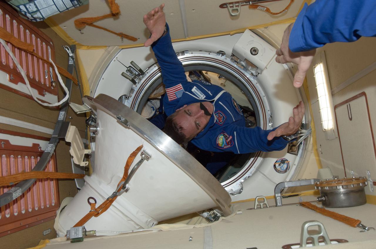 ISS035-E-010762 (29 March 2013) --- Expedition 35 Flight Engineer Roman Romanenko, whose stretched-out arm can be seen at upper right, was expecting to see NASA astronaut Chris Cassidy float into this scene in the Poisk or Mini-Research Module 2 (MRM2), but he might have been somewhat surprised to see the exaggerated mustache which Cassidy was sporting. Cassidy and two crewmates had earlier arrived at the orbital outpost by way of the Soyuz TMA-08M spacecraft.  One would imagine that Expedition 35 Commander Chris Hadfield (out of frame), who has a real mustache, likely checked out the one on Cassidy.