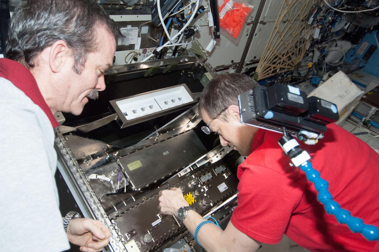 ISS035-E-013783 (2 April 2013) --- In the U.S. lab Destiny on the International Space Station, Expedition 35 Commander Chris Hadfield (right) and Flight Engineer Tom Marshburn remove the Video Baseband Signal Processor (VBSP) in order to replace it with a new Ku communication unit and its associated data and Ethernet cabling.