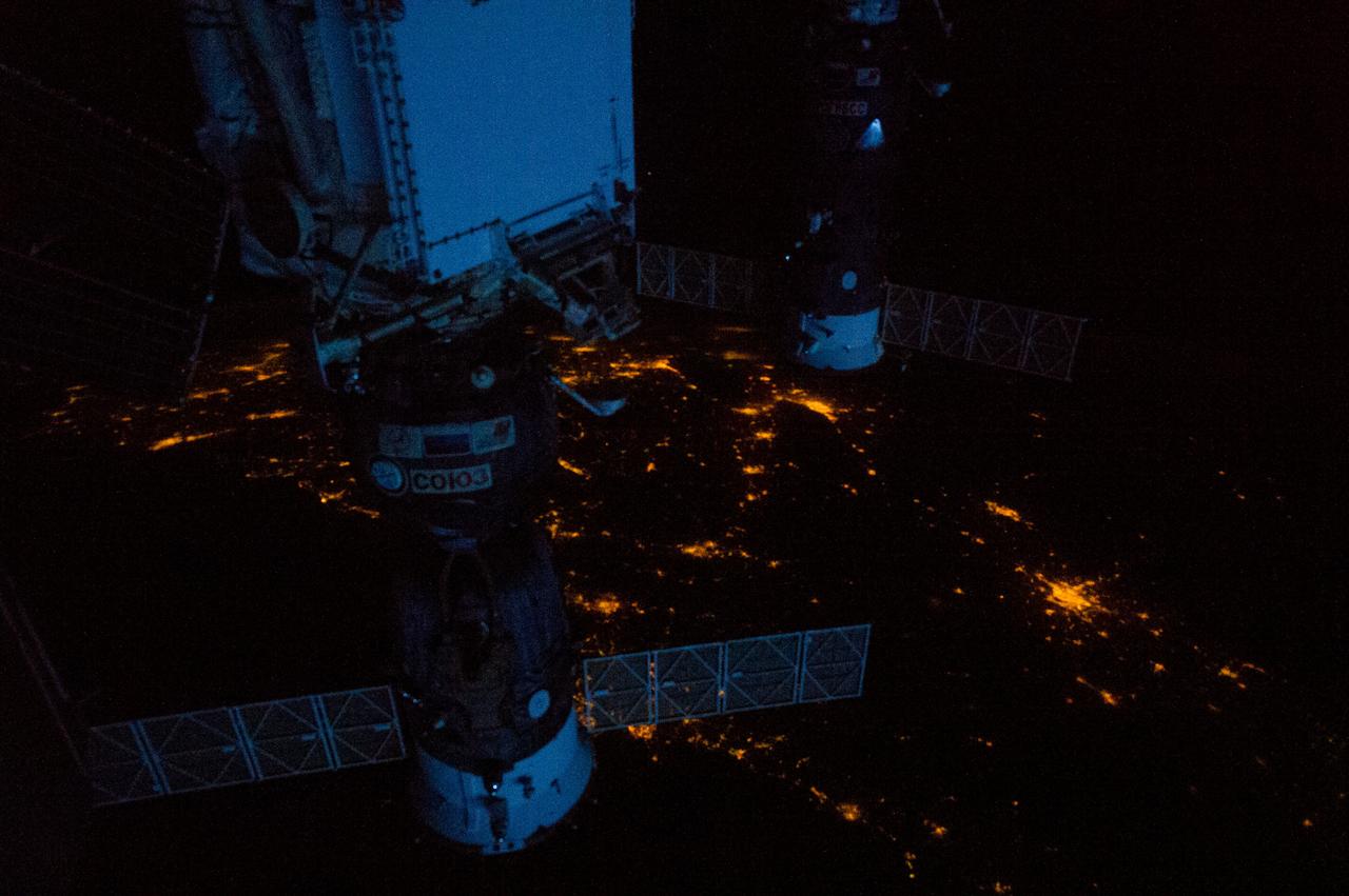 Earth observation taken by the Expedition 35 crew aboard the ISS. Night view of the docked Soyuz TMA-07M and Progress 50P spacecraft against a backdrop of city lights.