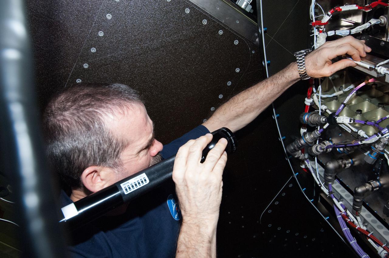 ISS035-E-018277 (11 April 2013) --- Expedition 35 Commander Chris Hadfield, astronaut with the Canadian Space Agency, installs the redundant Ku Communications 1 unit in Destiny to complete the refurbishment of the Ku system aboard the International Space Station. NASA astronaut Tom Marshburn (out of frame), Expedition 35 flight engineer, joined Hadfield for this work.