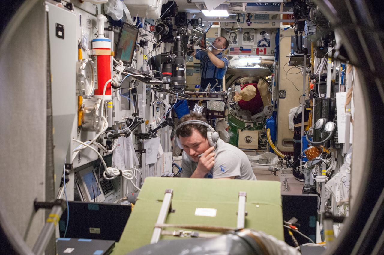ISS035-E-029752 (26 April 2013) ---  Russian cosmonauts Roman Romanenko, foreground, and  Alexander Misurkin busy themselves with various chores in the Zvezda service module aboard the Earth-orbiting International Space Station during the rendezvous and docking of the Progress 51 cargo craft.