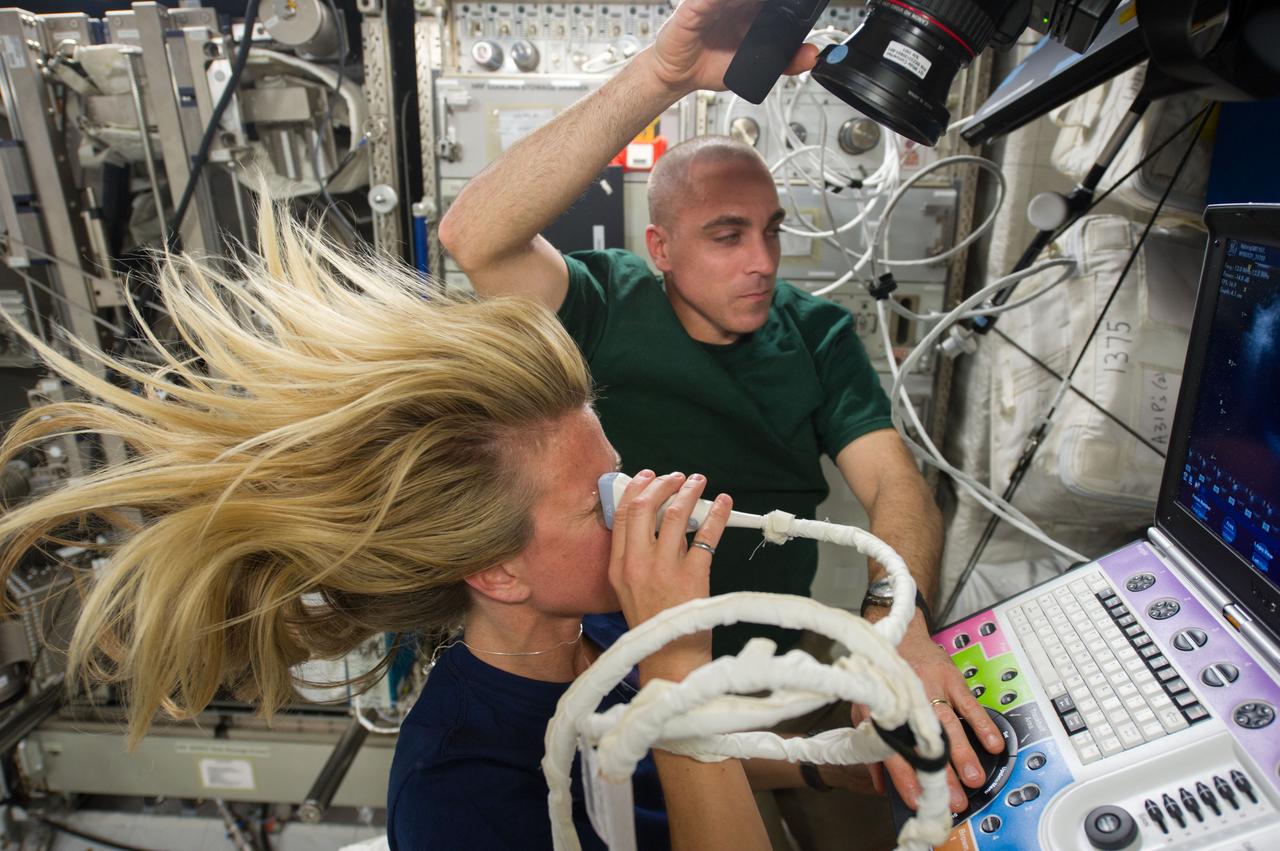 Astronaut Karen Nyberg,Expedition 37 flight engineer, assisted by astronaut Chris Cassidy, performs an Ocular Health (OH) Ultrasound 2 scan in the Destiny laboratory of the International Space Station.