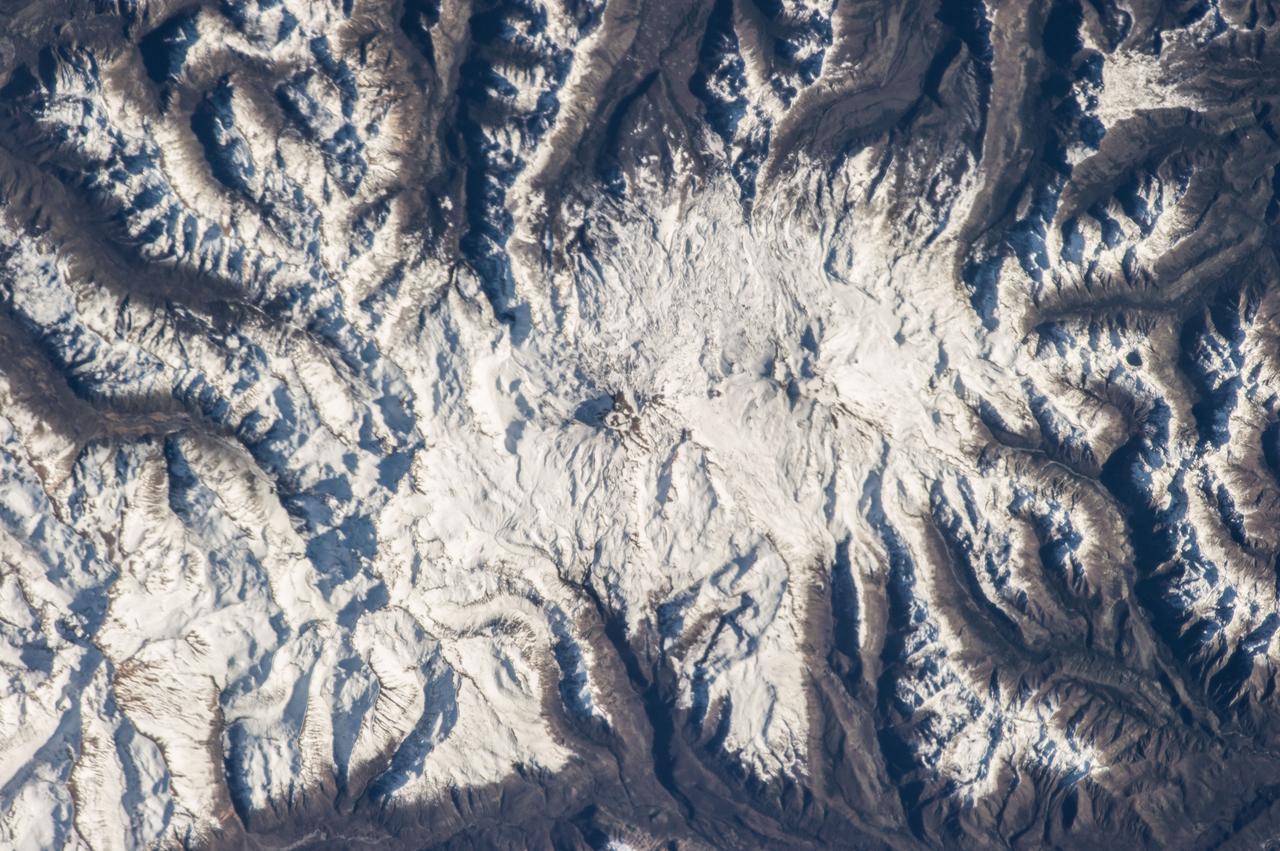 ISS036-E-007165 (11 June 2013) --- Nevados de Chillan, Chile is featured in this image photographed by an Expedition 36 crew member on the International Space Station. This photograph highlights a large volcanic area located near the Chile-Argentina border. Like other historically active volcanoes in the central Andes ranges, the Nevados de Chillan were created by upwelling magma generated by eastward subduction of the dense oceanic crust of the Pacific basin beneath the less dense continental crust of South America. Rising magmas associated with this type of tectonic environment frequently erupt explosively, forming widespread ash and ignimbrite layers. They can also produce less explosive eruptions that form voluminous lava flows – layering together with explosively erupted deposits to build the classic cone-shaped edifice of a stratovolcano over geologic time. The Nevados de Chillan includes three distinct volcanic structures, built within three overlapping calderas that extend along a north-northwest to south-southeast line. The snow-capped volcanic complex sits within the glaciated terrain of the central Andes – glacial valleys are visible at upper left, upper right, and lower right. The northwestern end of the chain is occupied by the 3,212-meter-high Cerro Blanco (also known as Volcan Nevado). The 3,089-meter-high Volcan Viejo (also known as Volcan Chillan) sits at the southeastern end; this volcano was active during the 17th-19th centuries. A group of lava domes known as Volcan Nuevo formed to the northwest of Volcan Viejo between 1906-1945, followed by an even younger dome complex that formed between 1973-1986 (Volcan Arrau; not indicated on the image). The last reported volcanic activity at Nevados de Chillan took place in 2009 (according to the Smithsonian Institution’s Global Volcanism Network).