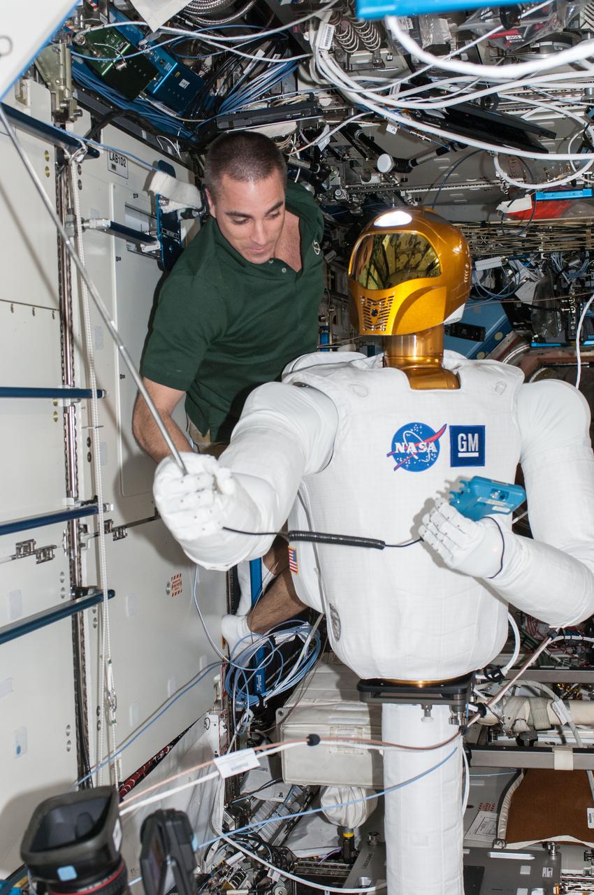 ISS036-E-013170 (28 June 2013) --- NASA astronaut Chris Cassidy, Expedition 36 flight engineer, works with Robonaut 2, the first humanoid robot in space, during a round of ground-commanded tests in the Destiny laboratory of the International Space Station. R2 was assembled earlier this week for several days of data takes by the payload controllers at the Marshall Space Flight Center.