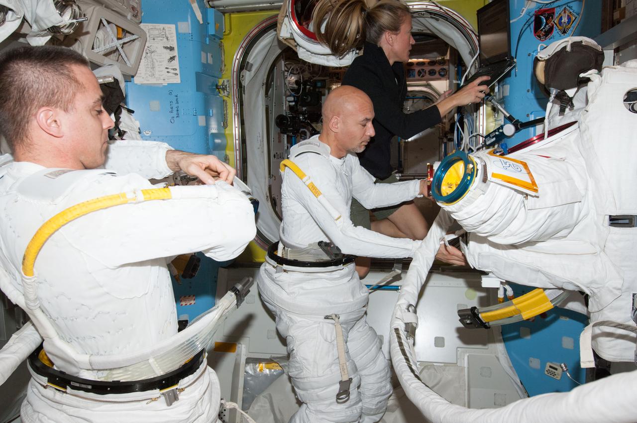 ISS036-E-014713 (3 July 2013) --- NASA astronaut Chris Cassidy (left) and European Space Agency astronaut Luca Parmitano, both Expedition 36 flight engineers, don their Extravehicular Mobility Unit (EMU) spacesuits for a ?dry run? in the International Space Station?s Quest airlock in preparation for the first of two sessions of extravehicular (EVA) scheduled for July 9 and July 16. NASA astronaut Karen Nyberg, flight engineer, uses a computer in the background.