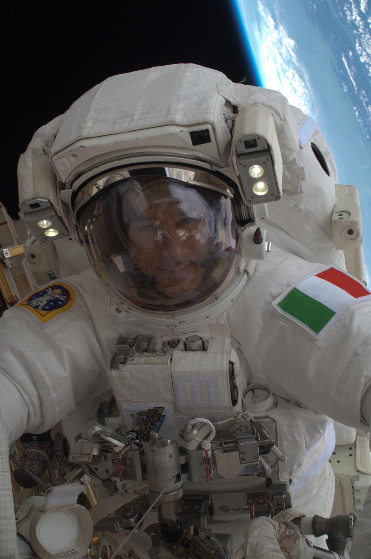 European Space Agency astronaut Luca Parmitano, Expedition 36 flight engineer, participates in a session of extravehicular activity (EVA) as work continues on the International Space Station. Parmitano is inside a space suit with a blue sliver of Earth visible in the background. 
