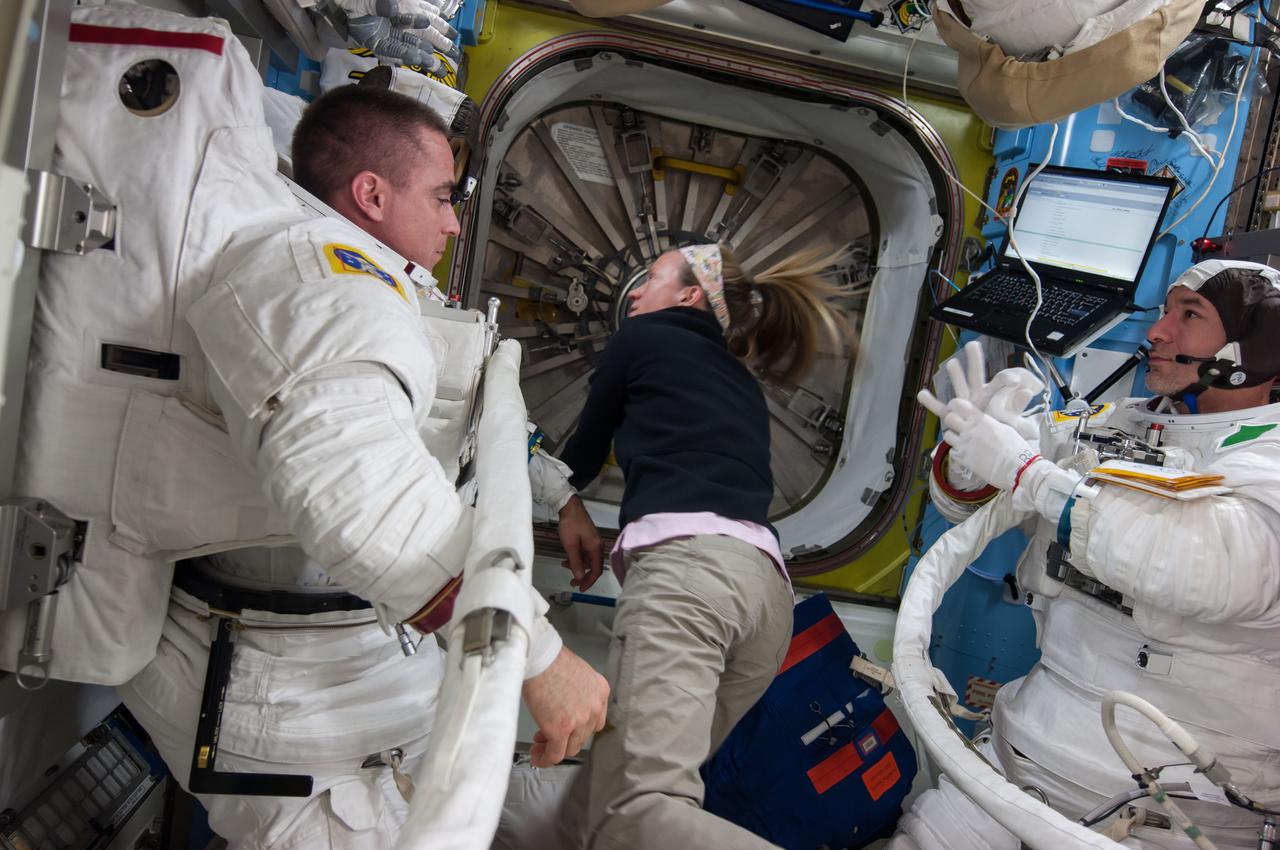 ISS036-E-017389 (8 July 2013) --- NASA astronaut Chris Cassidy (left) and European Space Agency astronaut Luca Parmitano, both Expedition 36 flight engineers, are pictured in the Quest airlock of the International Space Station as they prepare for the start of a session of extravehicular activity (EVA). Cassidy and Parmitano are wearing Extravehicular Mobility Unit (EMU) spacesuits. NASA astronaut Karen Nyberg, flight engineer, assists her crew members.
