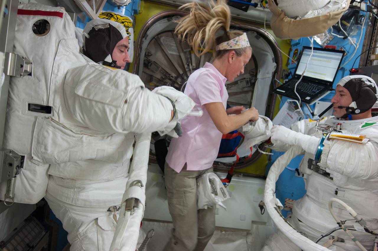 ISS036-E-017393 (8 July 2013) --- NASA astronaut Chris Cassidy (left) and European Space Agency astronaut Luca Parmitano, both Expedition 36 flight engineers, are pictured in the Quest airlock of the International Space Station as they prepare for the start of a session of extravehicular activity (EVA). Cassidy and Parmitano are wearing Extravehicular Mobility Unit (EMU) spacesuits. NASA astronaut Karen Nyberg, flight engineer, assists her crew members.
