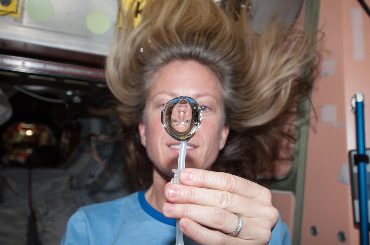 ISS036-E-018290 (12 July 2013) --- NASA astronaut Karen Nyberg, Expedition 36 flight engineer, squeezes a water bubble out of her beverage container, showing her image refracted, in the Unity node of the International Space Station.