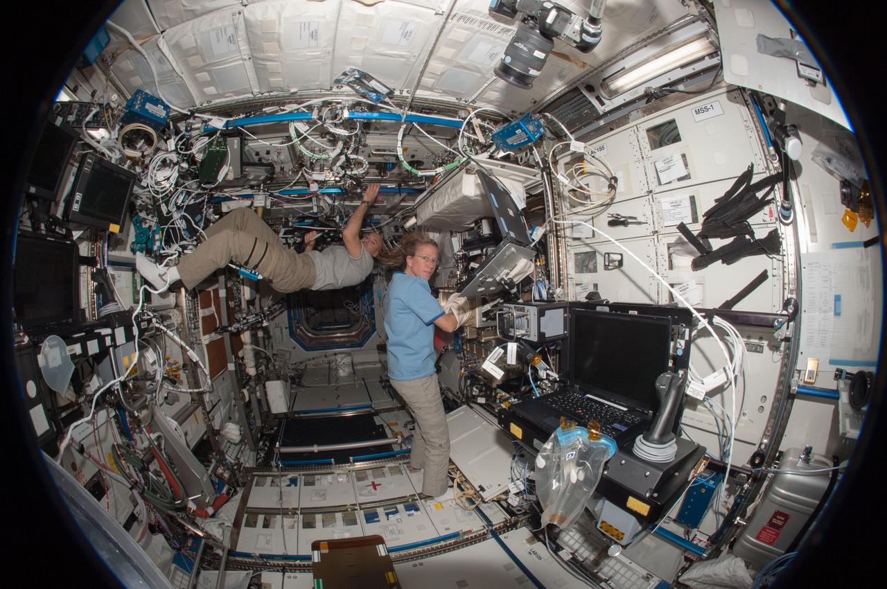 ISS036-E-019781 (24 June 2013) --- A fisheye lens attached to an electronic still camera was used to capture this image of European Space Agency astronaut Luca Parmitano and NASA astronaut Karen Nyberg, both Expedition 36 flight engineers, as they work in the Destiny laboratory of the International Space Station.