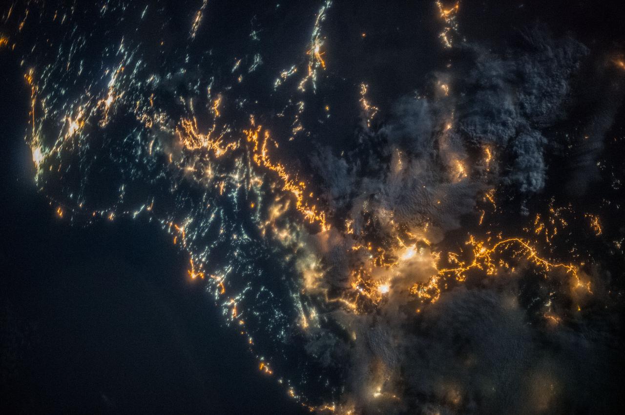ISS036-E-025802 (26 July 2013) --- A nighttime view of southwestern Saudi Arabia is featured in this image photographed by an Expedition 36 crew member on the International Space Station. In addition to city lights, patchy cloud cover partially obscures and blurs city lights, especially in the vicinity of Khamis Mushait and Abha. While much of the country is lightly populated desert ? and relatively dark at night due to lack of city and roadway lights ? the southwestern coastal region has more moderate climate and several large cities. Three brightly lit urban centers are visible at top left; Jeddah, Mecca, and Taif. Jeddah is the gateway city for Islamic pilgrims going to nearby Mecca (a religious journey known as the hajj). Taif to the east is located on the slopes of the Sarawat Mountains, and provides a summer retreat for the Saudi government from the desert heat of the capital city of Riyadh. Bright yellow-orange lighting marks highways that parallel the trend of the Asir Mountains at center, connecting Mecca to the resort cities of Al Bahah and Abha (lower right). Smaller roadways, lit with blue lights, extend to the west to small cities along the Red Sea coastline. The bright yellow-orange glow of the city of Abha is matched by that of the city of Khamis Mushait (or Khamis Mushayt) to the northeast. The brightly lit ribbon of highway continues onward towards other large cities to the south (Jazan, not shown) and southeast (Najran, not shown).