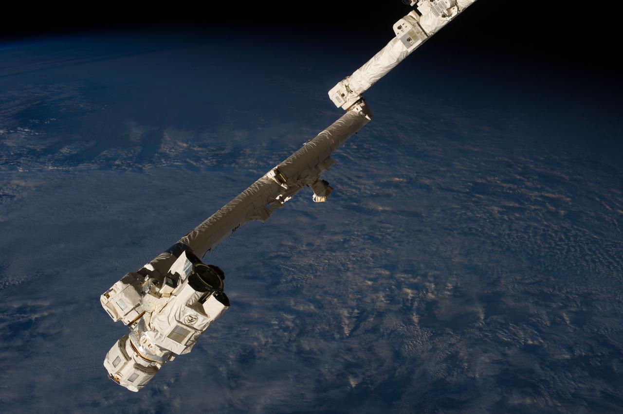 View of Space Station Remote Manipulator System (SSRMS) extended arm with a dark,cloudy Earth in the background. Photo was taken by an Expedition 36 crew member on board the International Space Station (ISS). Per Twitter message: #CanadaArm2 poised and ready to support capture of #HTV4 in just a couple weeks.