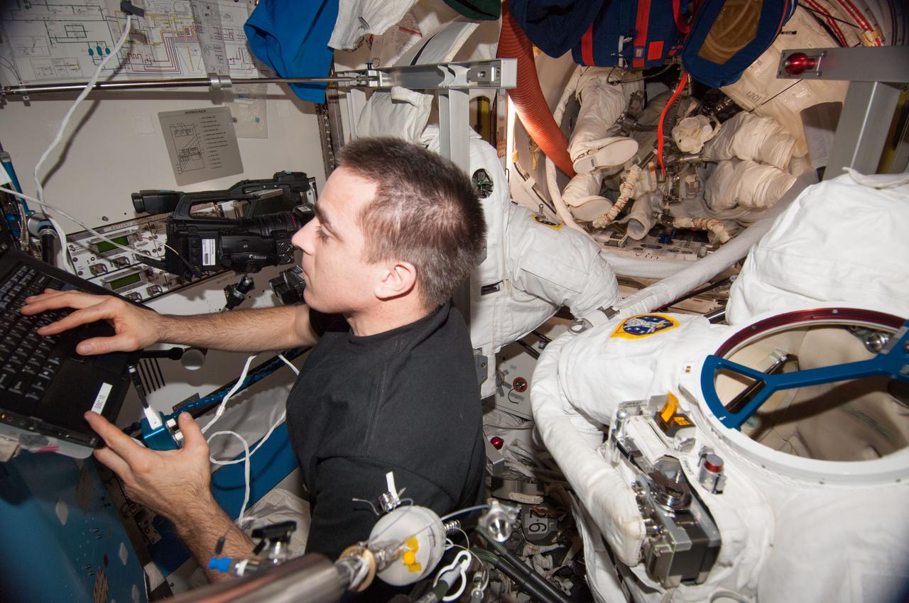 ISS036-E-027931 (2 Aug. 2013) --- NASA astronaut Chris Cassidy, Expedition 36 flight engineer, uses a computer while working with Extravehicular Mobility Unit (EMU) spacesuits in the Quest airlock of the International Space Station.