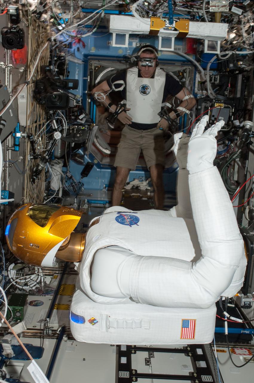 ISS036-E-029109 (6 Aug. 2013) --- In the International Space Station’s Destiny laboratory, NASA astronaut Chris Cassidy, Expedition 36 flight engineer, wears tele-operation gear consisting of a vest, gloves and visor to telerobotically test Robonaut 2’s maneuvers. Cassidy was able to manipulate R2’s head, neck, arms and fingers telerobotically through his own movements as well as through verbal commands.
