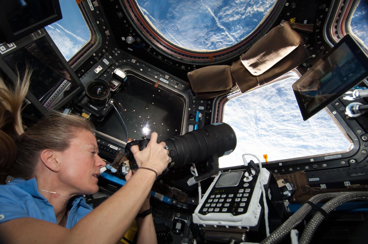 ISS036-E-029853 (9 Aug. 2013) --- At the windows in the International Space Station?s Cupola, NASA astronaut Karen Nyberg, Expedition 36 flight engineer, uses a digital still camera to photograph the approaching unpiloted Japanese "Kounotori" H2 Transfer Vehicle-4 (HTV-4).