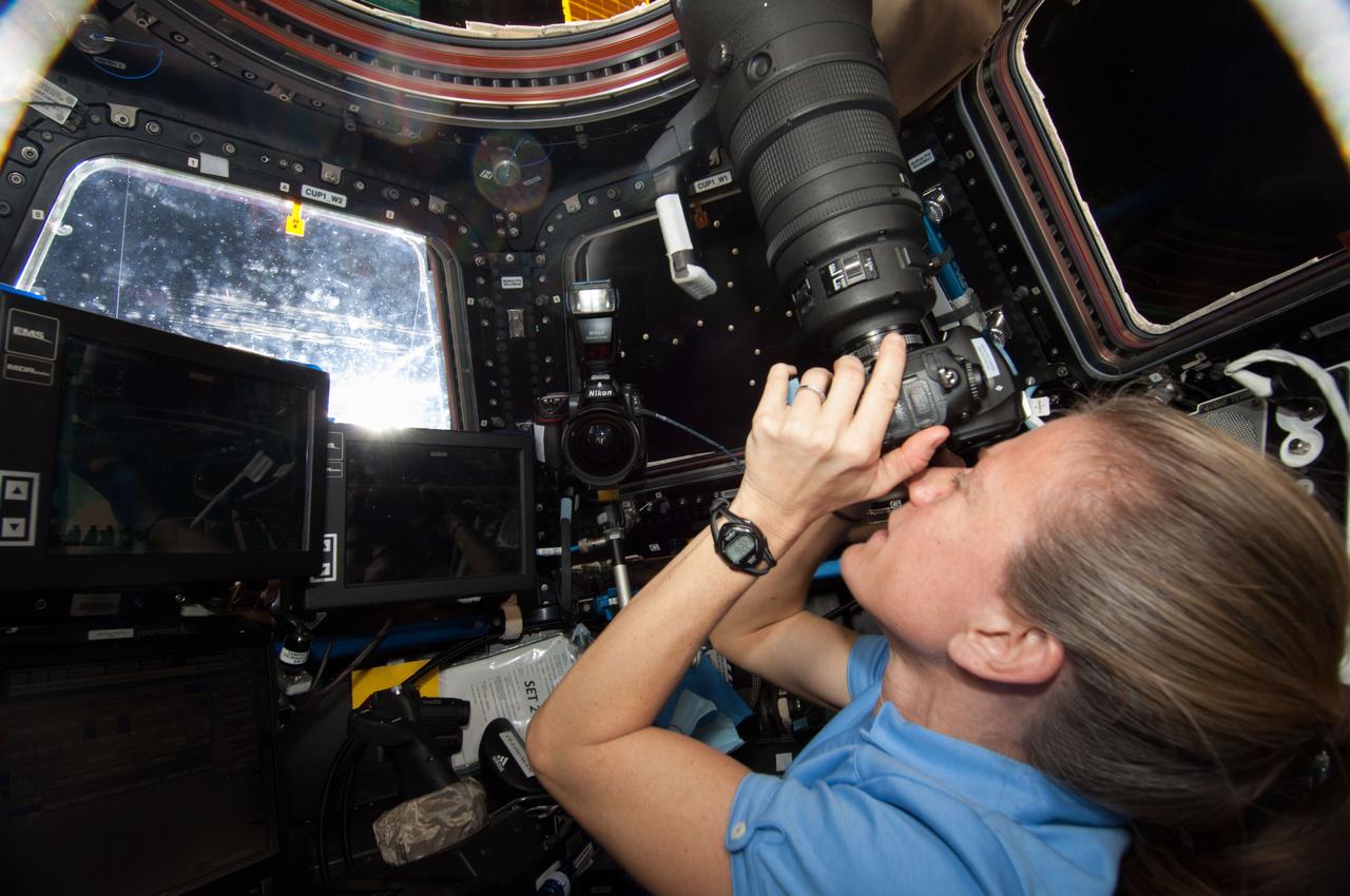 ISS036-E-029856 (9 Aug. 2013) --- At the windows in the International Space Station?s Cupola, NASA astronaut Karen Nyberg, Expedition 36 flight engineer, uses a digital still camera to photograph the approaching unpiloted Japanese "Kounotori" H2 Transfer Vehicle-4 (HTV-4).