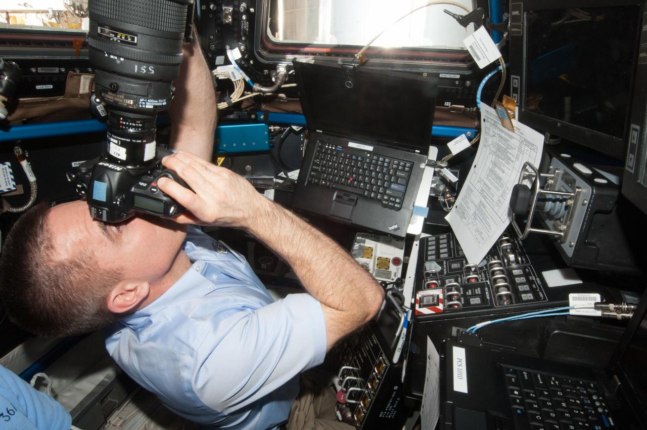 ISS036-E-029897 (9 Aug. 2013) --- At the windows in the International Space Station?s Cupola, NASA astronaut Chris Cassidy, Expedition 36 flight engineer, uses a digital still camera to photograph the approaching unpiloted Japanese "Kounotori" H2 Transfer Vehicle-4 (HTV-4).