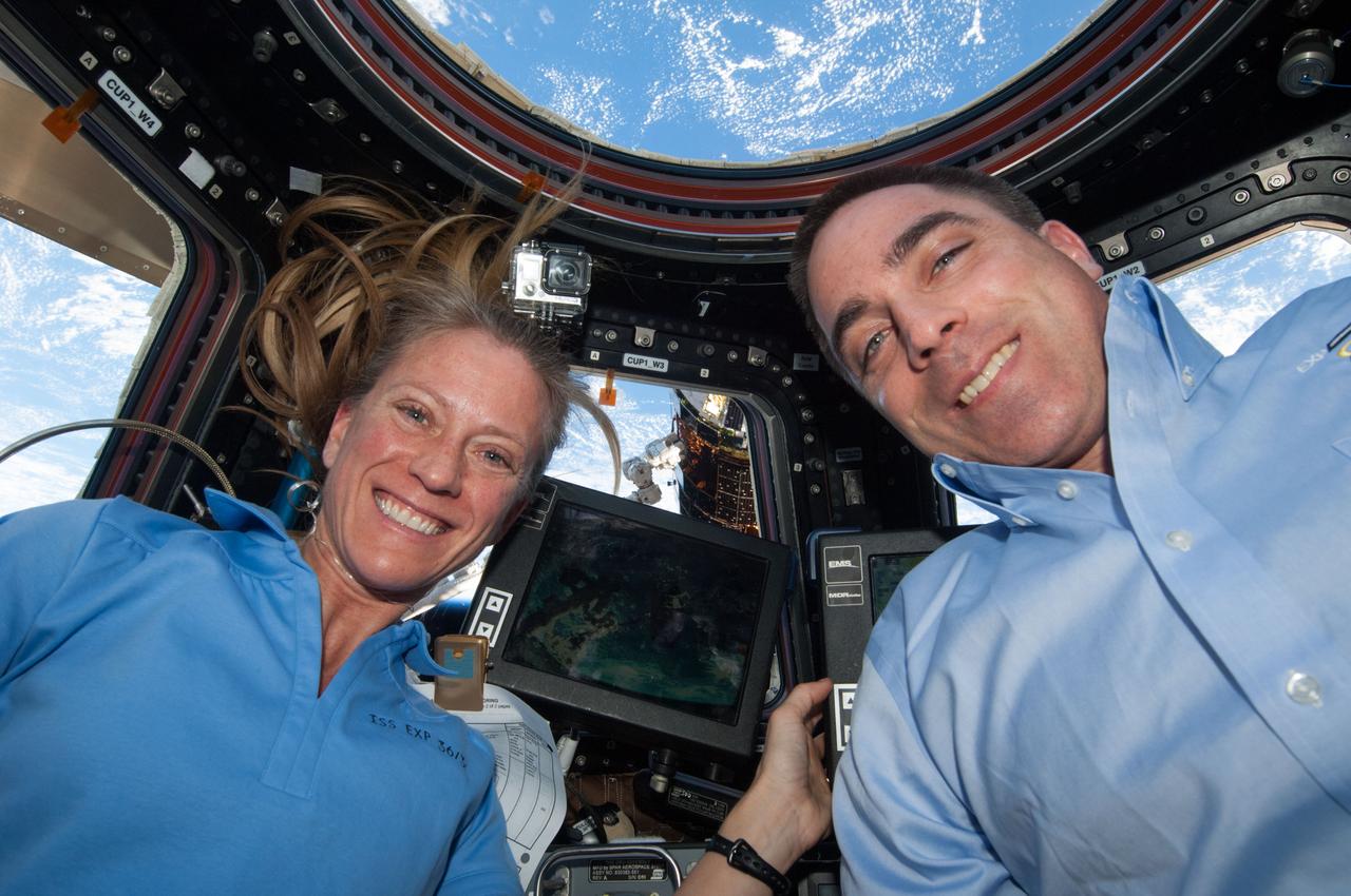 NASA astronauts Karen Nyberg and Chris Cassidy,  both Expedition 36 flight engineers, are pictured at the robotic workstation in the Cupola of the International Space Station during rendezvous operations with the approaching unpiloted Japanese Kounotori H2 Transfer Vehicle-4 (HTV-4). The HTV-4 is visible from the Cupola window. Also sent as Twitter message.
