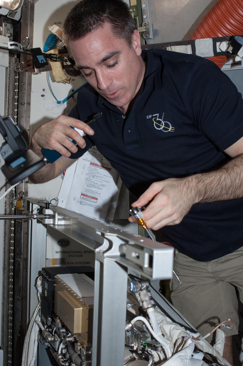ISS036-E-038552 (30 Aug. 2013) --- NASA astronaut Chris Cassidy, Expedition 36 flight engineer, works on an Extravehicular Mobility Unit (EMU) spacesuit in the Quest airlock of the International Space Station.