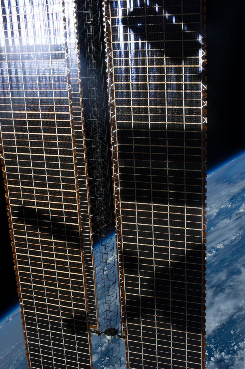View of the solar array over an Earth limb taken during a day pass by an Expedition 36 crew member on board the International Space Station (ISS).  Per Twitter message: Our Space Station casting shadows on itself.