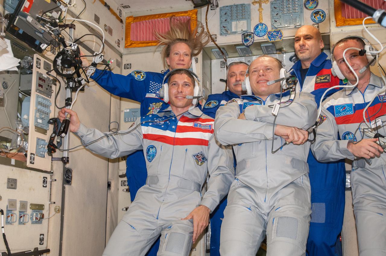 ISS037-E-002747 (25 Sept. 2013) --- The new six-member Expedition 37 crew gathers in the Zvezda Service Module of the International Space Station for a welcoming ceremony shortly after the TMA-10M spacecraft docked with the station, bringing NASA astronaut Michael Hopkins (left, front row), Russian cosmonauts Oleg Kotov (center, front row) and Sergey Ryazanskiy (right, front row), all flight engineers. Pictured from the left (back row) are NASA astronaut Karen Nyberg, flight engineer; Russian cosmonaut Fyodor Yurchikhin, commander; and European Space Agency astronaut Luca Parmitano, flight engineer.