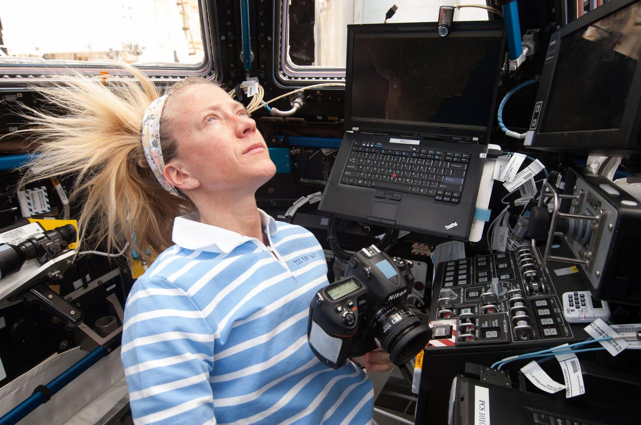 ISS037-E-002792 (23 Sept. 2013) --- Positioned in the Cupola of the International Space Station with a still camera in hand, Expedition 37 Flight Engineer Karen Nyberg eyeballs a potential photo target on Sept. 23, 2013. Nyberg, along with European Space   Agency astronaut Luca Parmitano and Russian cosmonaut Fyodor Yurchikhin (both out of frame), will be welcoming three more crewmates in a couple of days following a scheduled Soyuz launch from Kazakhstan on Sept. 26, Kazakh time.