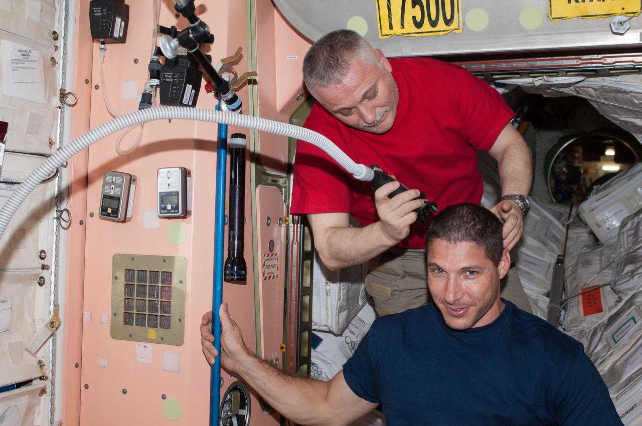 ISS037-E-006565 (5 Oct. 2013) --- Russian cosmonaut Fyodor Yurchikhin, Expedition 37 commander, trims the hair of NASA astronaut Michael Hopkins, flight engineer, in the Unity node of the International Space Station. Yurchikhin used hair clippers fashioned with a vacuum device to garner freshly cut hair.