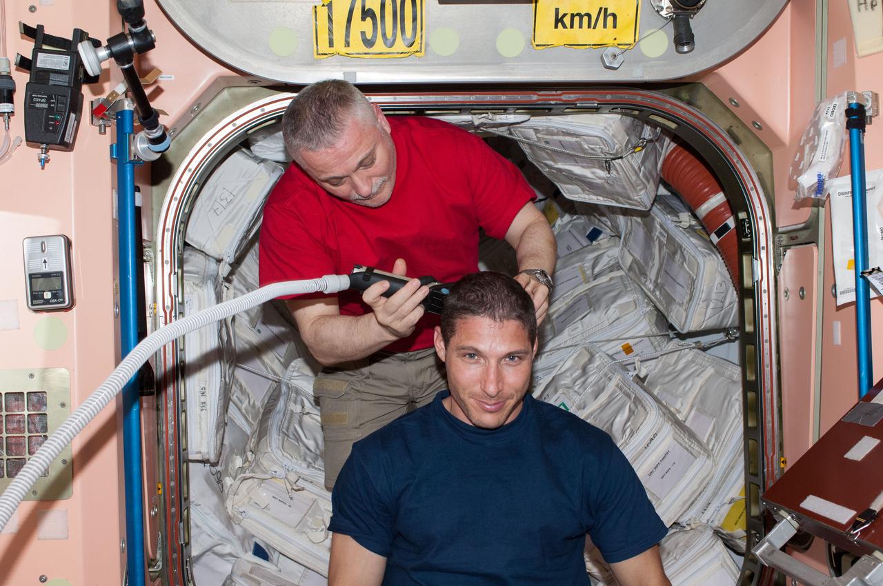 ISS037-E-006568 (5 Oct. 2013) --- Russian cosmonaut Fyodor Yurchikhin, Expedition 37 commander, trims the hair of NASA astronaut Michael Hopkins, flight engineer, in the Node 1 module, called Unity. Yurchikhin used hair clippers fashioned with a vacuum device to garner freshly cut hair.