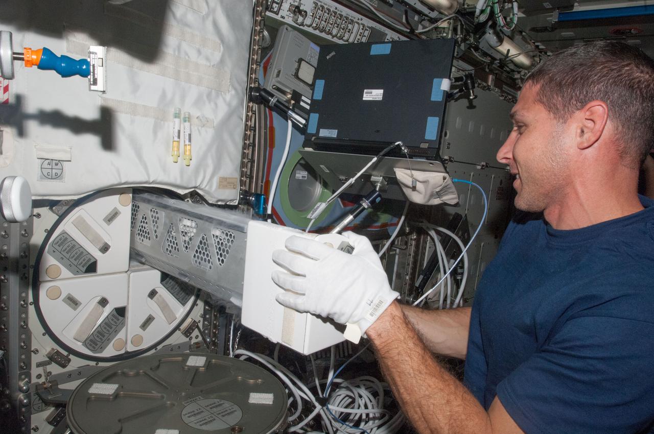 ISS037-E-010711 (5 Oct. 2013) --- In the International Space Station’s Destiny laboratory, NASA astronaut Michael Hopkins, Expedition 37 flight engineer, removes a dewar tray from the Minus Eighty Laboratory Freezer for ISS (MELFI) in order to insert biological samples into the trays.
