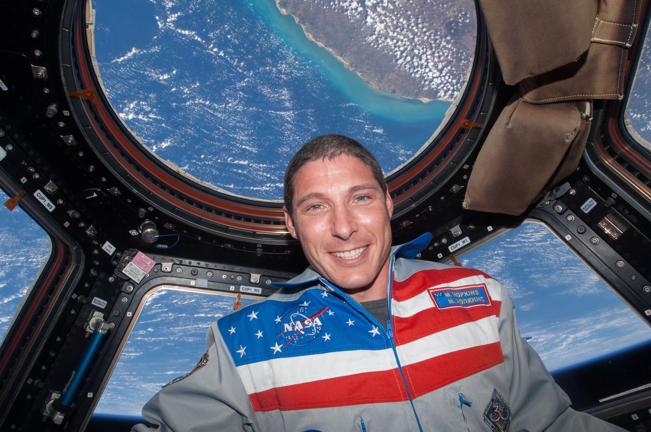 ISS037-E-011232 (14 Oct. 2013) --- NASA astronaut Mike Hopkins, Expedition 37 flight engineer, like all International Space Station inhabitants, enjoys time in the Cupola, which affords the most broad views of Earth. "Behind" Hopkins can be seen the northern coast of Brazil, including the Acarau River delta in the state of Ceara, just west of the city of Fortaleza (out of frame).