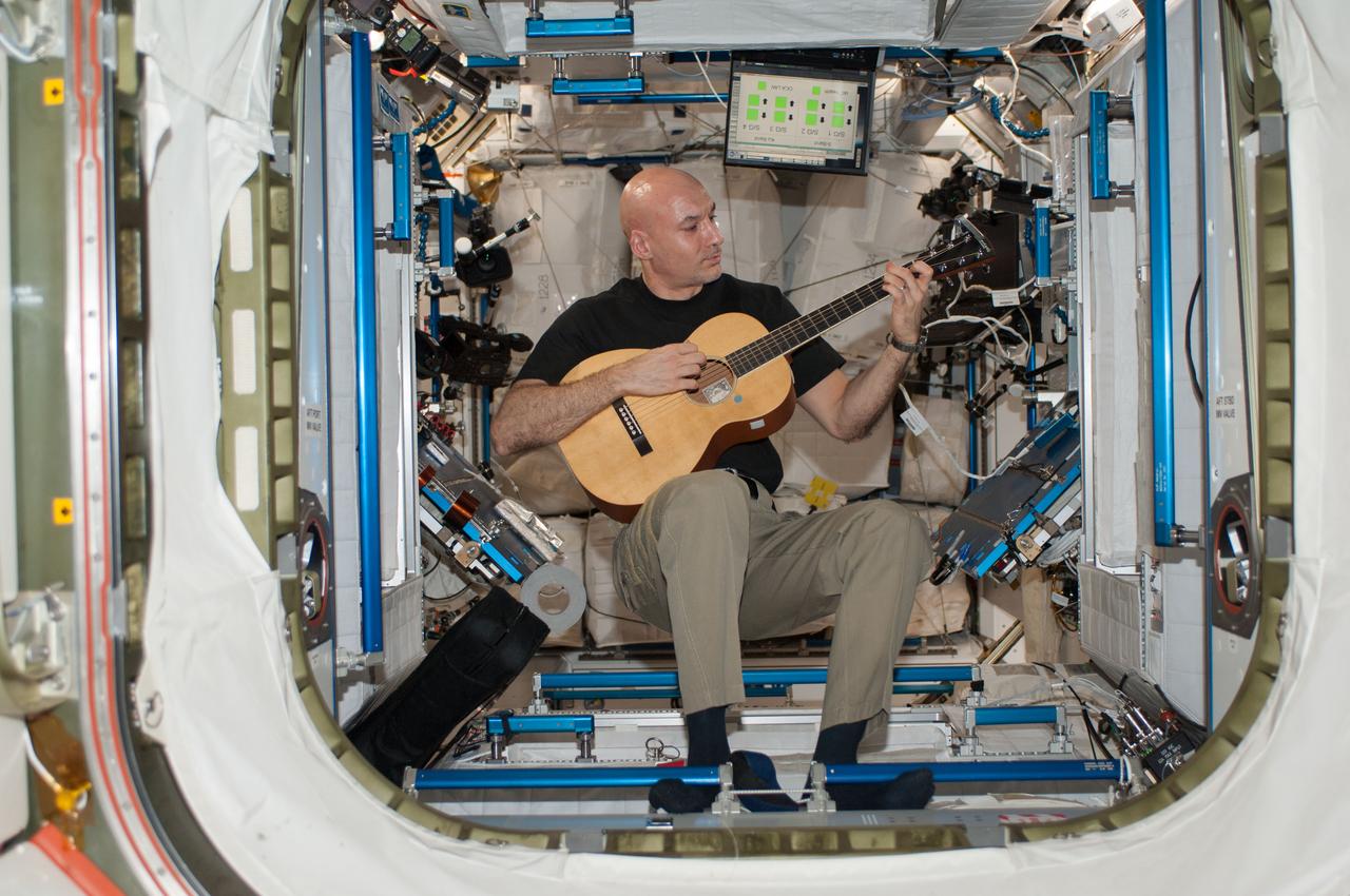 ISS037-E-021308 (26 Oct. 2013) --- European Space Agency astronaut Luca Parmitano, Expedition 37 flight engineer, plays a guitar during some of his off-duty time in the Harmony node of the International Space Station.