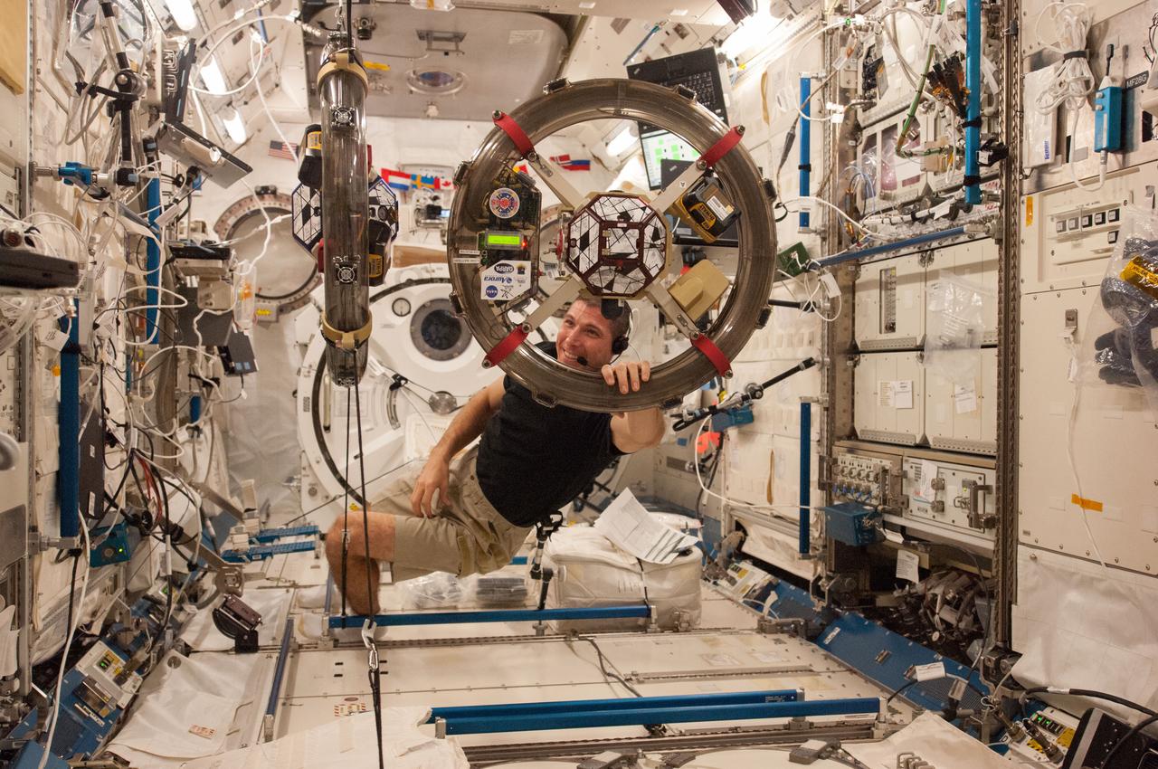 ISS037-E-025866 (4 Nov. 2013) --- In the International Space Station?s Kibo laboratory, NASA astronaut Michael Hopkins, Expedition 37 flight engineer, conducts a session with a pair of bowling-ball-sized free-flying satellites known as Synchronized Position Hold, Engage, Reorient, Experimental Satellites, or SPHERES. Surrounding the two SPHERES mini-satellites is ring-shaped hardware known as the Resonant Inductive Near-field Generation System, or RINGS. SPHERES-RINGS seeks to demonstrate wireless power transfer between satellites at a distance for enhanced operations.