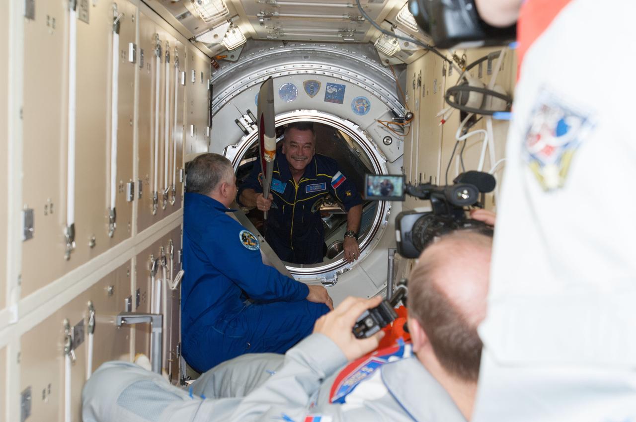 ISS037-E-028203 (7 Nov. 2013) --- In the International Space Station's Rassvet Mini-Research Module 1 (MRM1), Russian cosmonaut Fyodor Yurchikhin, Expedition 37 commander, welcomes Russian cosmonaut Mikhail Tyurin (holding the Olympic torch), Expedition 38 flight engineer, after arriving onboard a Soyuz spacecraft with Japan Aerospace Exploration Agency astronaut Koichi Wakata and NASA astronaut Rick Mastracchio, both Expedition 38 flight engineers. Russian cosmonaut Oleg Kotov (foreground), Expedition 37 flight engineer, captures the event with a video camera.
