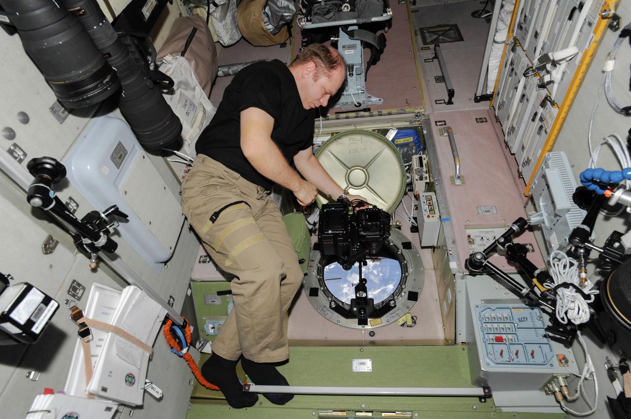 ISS038-E-005016 (20 Nov. 2013) --- At a window in the International Space Station?s Zvezda Service Module, Russian cosmonaut Oleg Kotov, Expedition 38 commander, uses a digital camera photospectral system to perform a session for the Albedo Experiment. The experiment measures Earth?s albedo, or the amount of solar radiation reflected from the surface, in the hopes to develop methods to harness the reflected radiation to supplement the station?s power supply. The light reflection phenomenon is measured in units called albedo.