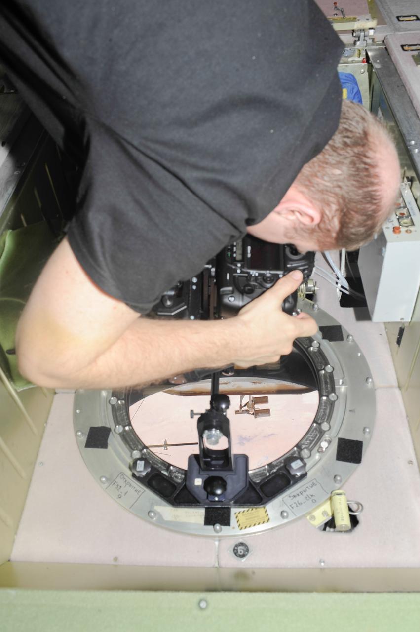 ISS038-E-005019 (20 Nov. 2013) --- At a window in the International Space Station?s Zvezda Service Module, Russian cosmonaut Oleg Kotov, Expedition 38 commander, uses a digital camera photospectral system to perform a session for the Albedo Experiment. The experiment measures Earth?s albedo, or the amount of solar radiation reflected from the surface, in the hopes to develop methods to harness the reflected radiation to supplement the station?s power supply. The light reflection phenomenon is measured in units called albedo.