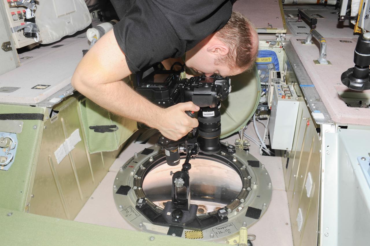 ISS038-E-005022 (20 Nov. 2013) --- At a window in the International Space Station?s Zvezda Service Module, Russian cosmonaut Oleg Kotov, Expedition 38 commander, uses a digital camera photospectral system to perform a session for the Albedo Experiment. The experiment measures Earth?s albedo, or the amount of solar radiation reflected from the surface, in the hopes to develop methods to harness the reflected radiation to supplement the station?s power supply. The light reflection phenomenon is measured in units called albedo.