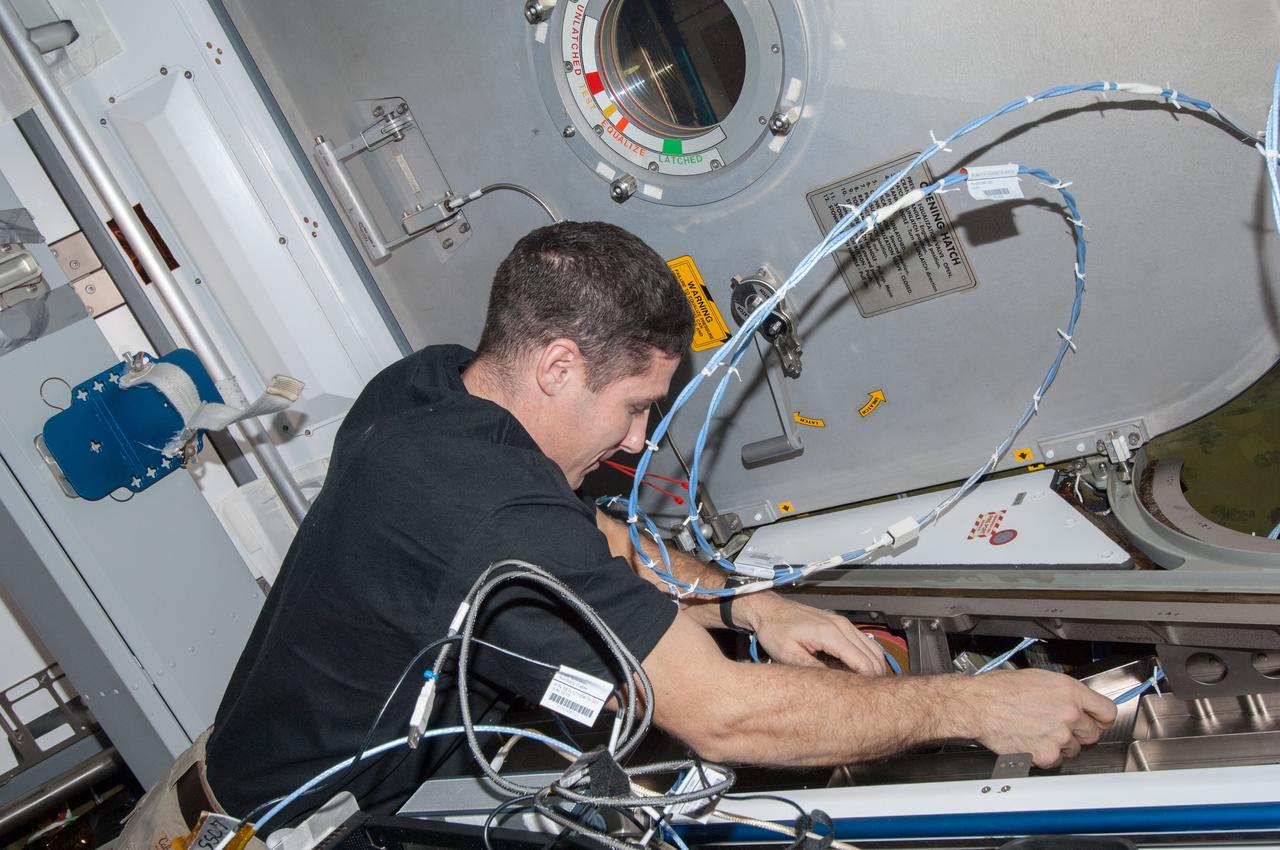 ISS038-E-008291 (24 Nov. 2013) --- NASA astronaut Michael Hopkins, Expedition 38 flight engineer, installs wire harnesses in the International Space Station?s Harmony node to support the installation of Ethernet video cables for the station?s local area network. These new cables will provide Ethernet connectivity to the visiting vehicles that dock to Harmony?s Earth-facing port.
