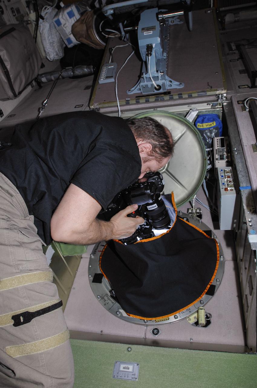 ISS038-E-010911 (2 Dec. 2013) --- At a window in the International Space Station?s Zvezda Service Module, Russian cosmonaut Oleg Kotov, Expedition 38 commander, uses a digital camera photospectral system during a session for the Seiner ocean photography experiment.