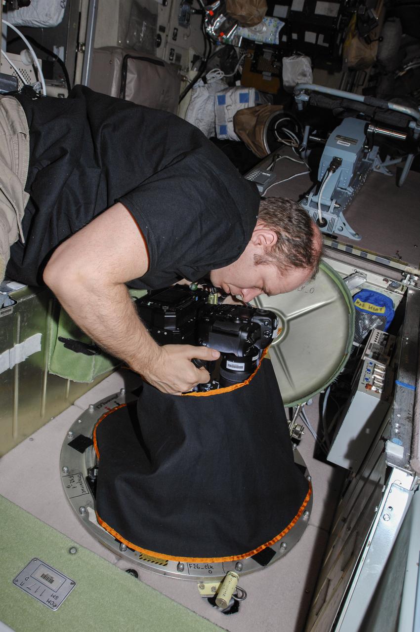ISS038-E-010916 (2 Dec. 2013) --- At a window in the International Space Station?s Zvezda Service Module, Russian cosmonaut Oleg Kotov, Expedition 38 commander, uses a digital camera photospectral system during a session for the Seiner ocean photography experiment.