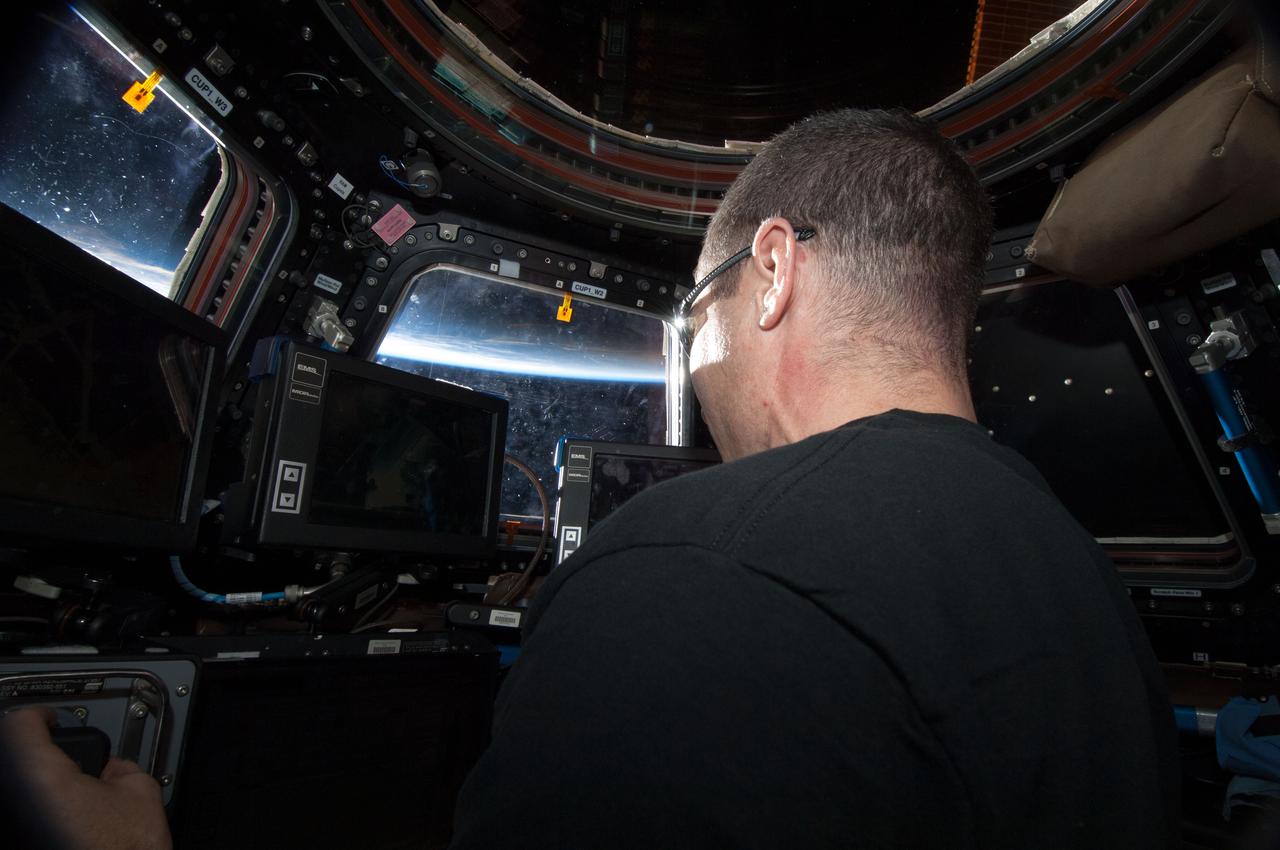 ISS038-E-011787 (4 Dec. 2013) --- NASA astronaut Michael Hopkins, Expedition 38 flight engineer, works the controls at the robotic workstation in the Cupola of the International Space Station.