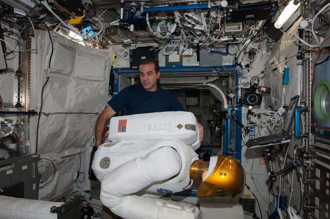 ISS038-E-013710 (9 Dec. 2013) --- In the International Space Station's Destiny laboratory, NASA astronaut Rick Mastracchio, Expedition 38 flight engineer, prepares Robonaut 2 for an upcoming ground-commanded firmware update that will support the installation of a pair of legs for the humanoid robot. R2 was designed to test out the capability of a robot to perform tasks deemed too dangerous or mundane for astronauts. Robonaut's legs are scheduled to arrive to the station aboard the SpaceX-3 commercial cargo mission in February 2014.