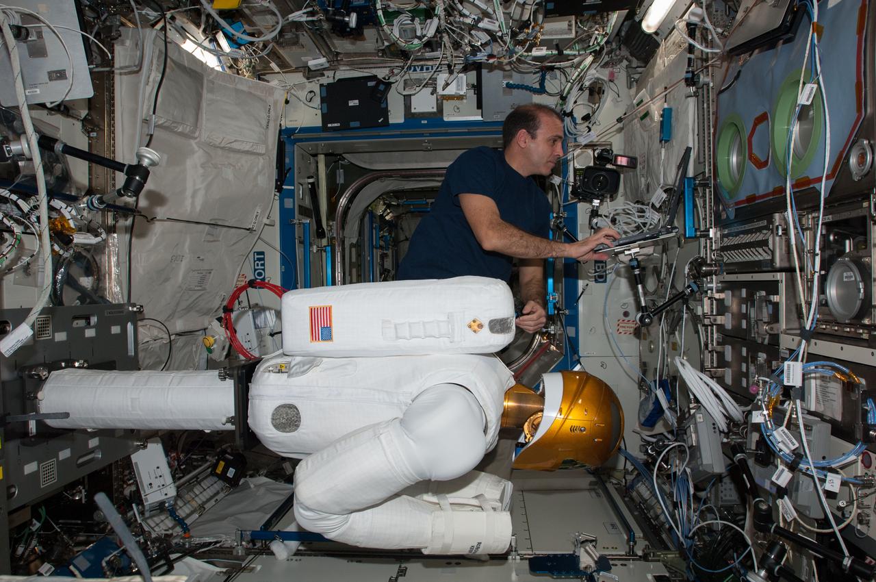 ISS038-E-013714 (9 Dec. 2013) --- In the International Space Station's Destiny laboratory, NASA astronaut Rick Mastracchio, Expedition 38 flight engineer, prepares Robonaut 2 for an upcoming ground-commanded firmware update that will support the installation of a pair of legs for the humanoid robot. R2 was designed to test out the capability of a robot to perform tasks deemed too dangerous or mundane for astronauts. Robonaut's legs are scheduled to arrive to the station aboard the SpaceX-3 commercial cargo mission in February 2014.