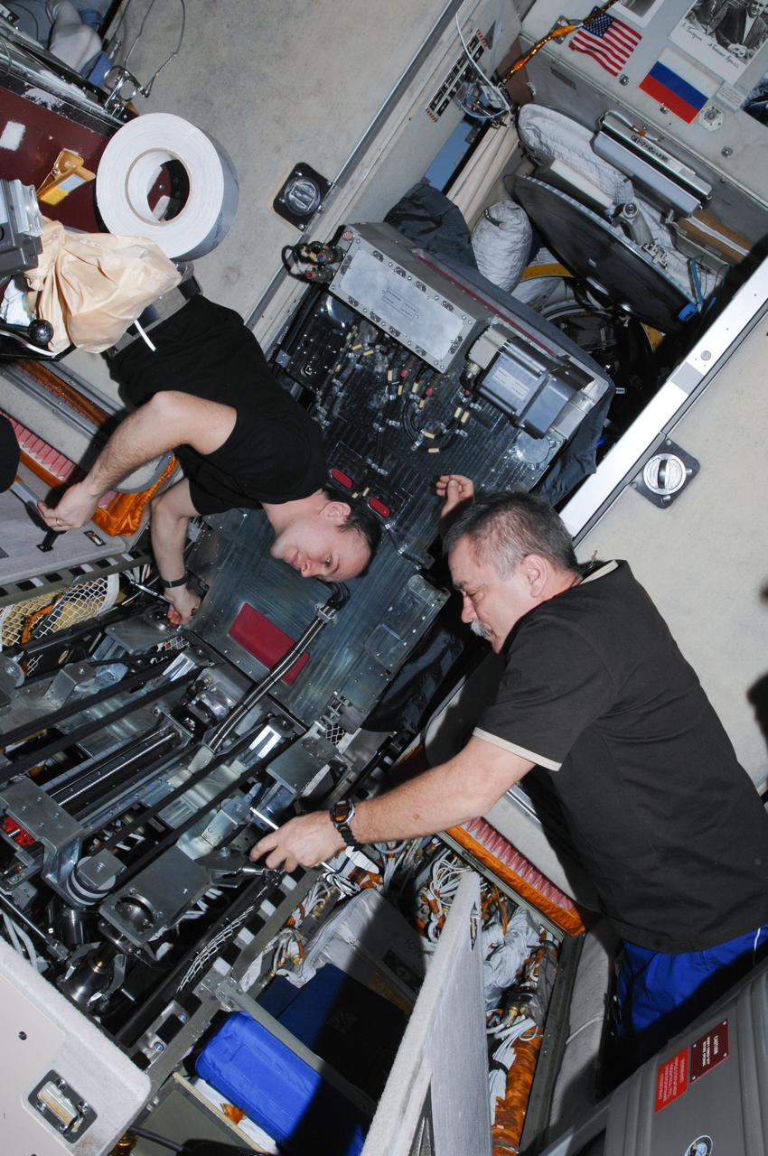 ISS038-E-013921 (11 Dec. 2013) --- Russian cosmonauts Sergey Ryazanskiy (left) and Mikhail Tyurin, both Expedition 38 flight engineers, perform routine in-flight maintenance on the Treadmill Vibration Isolation System (TVIS) in the Zvezda Service Module of the International Space Station.