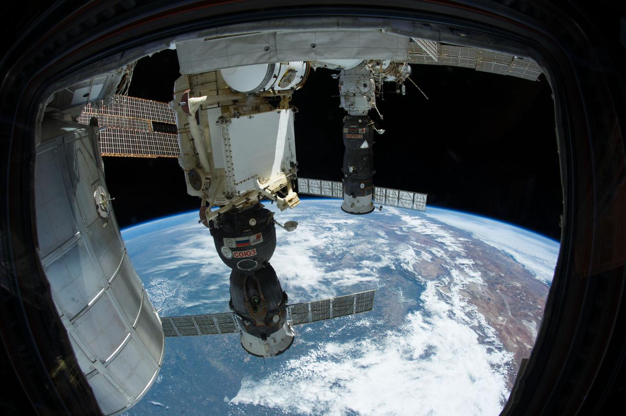 ISS038-E-015274 (12 Dec. 2013) --- The Permanent Multipurpose Module (PMM), the Soyuz 37 (TMA-11M) spacecraft  (center) docked to the Rassvet Mini-Research Module 1 (MRM1) and the Progress 52 resupply vehicle  (background) docked to the Pirs Docking Compartment are featured in this image photographed by an Expedition 38 crew member from a window in the Cupola of the International Space Station. A blue and white part of Earth provides the backdrop for the scene.